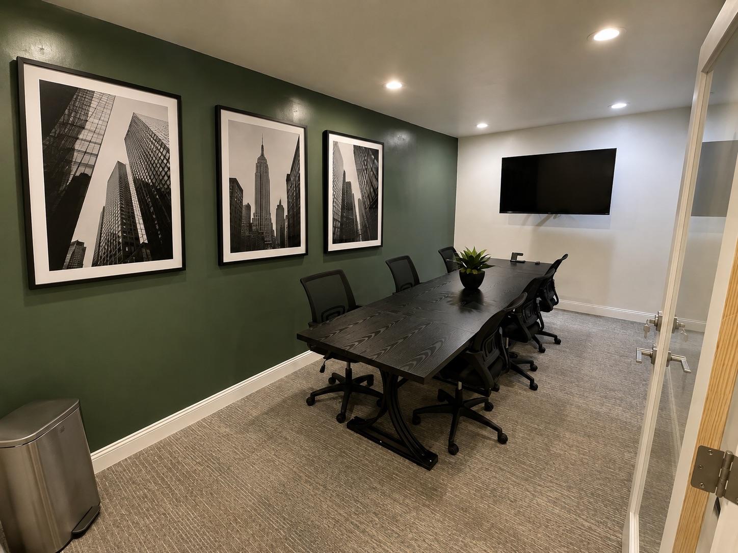 Private meeting room with conference table, presentation screen, and seating for team discussions